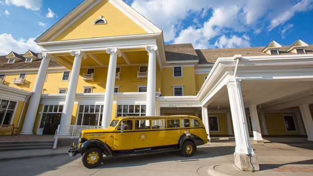 Front of Lake Yellowstone historic hotel with vintage yellow tour bus in front